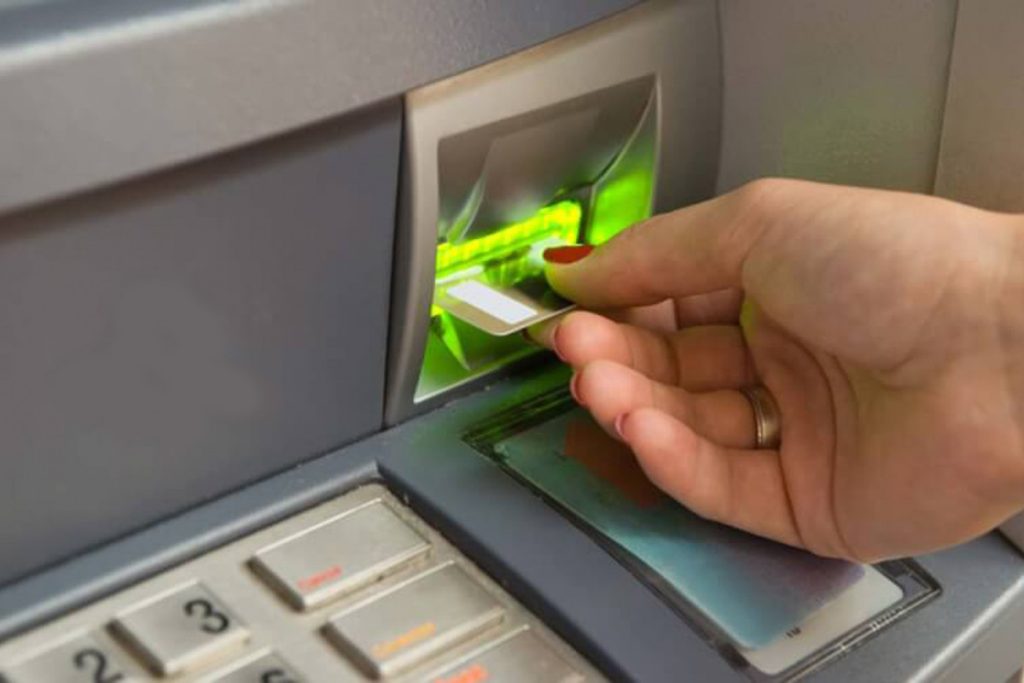 Eine Geste mit der Karte beim Abheben von Geld am Geldautomaten, die Ihnen den Urlaub verderben kann: Alle Banken warnen davor