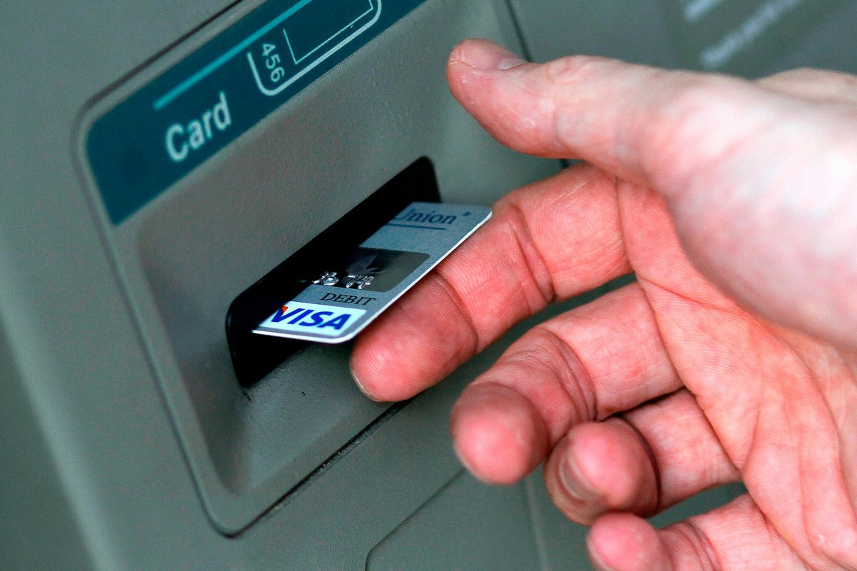 Eine Geste mit der Karte beim Abheben von Geld am Geldautomaten, die Ihnen den Urlaub verderben kann: Alle Banken warnen davor